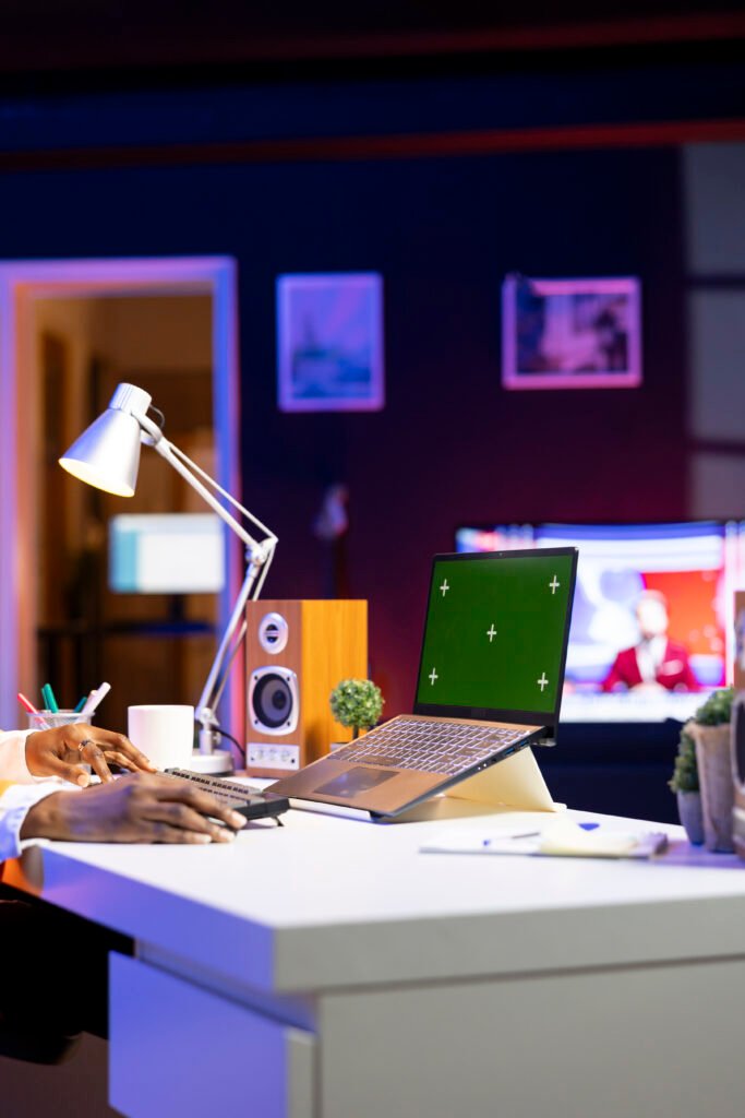 person at home office desk using green screen mockup laptop